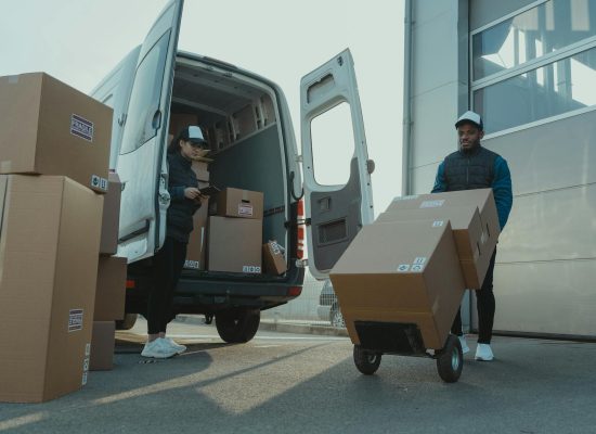 Two couriers load boxes into a van for shipment, showcasing logistics and teamwork.